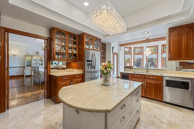 kitchen with a center island, sink, light stone countertops, appliances with stainless steel finishes, and a notable chandelier