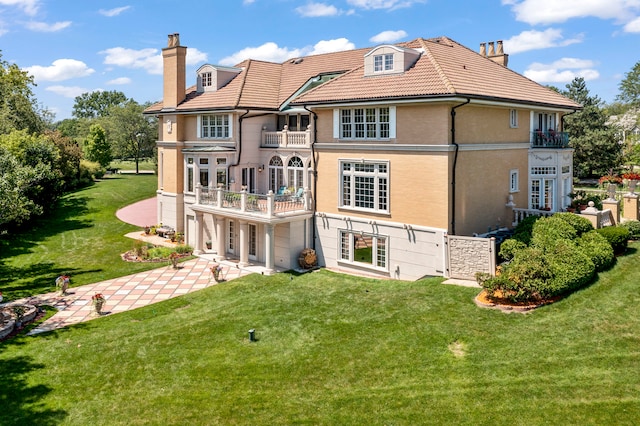 rear view of property with a balcony and a yard