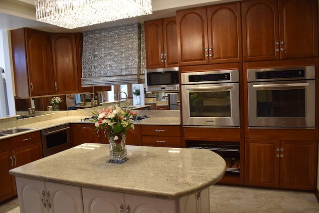 kitchen with a center island, light stone counters, stainless steel appliances, and an inviting chandelier