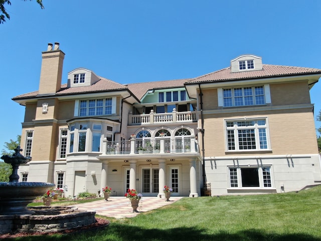 back of house with a yard, a balcony, and a patio