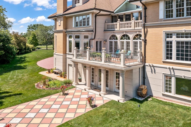 rear view of property with a yard and a balcony