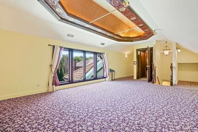 carpeted empty room featuring a raised ceiling and lofted ceiling