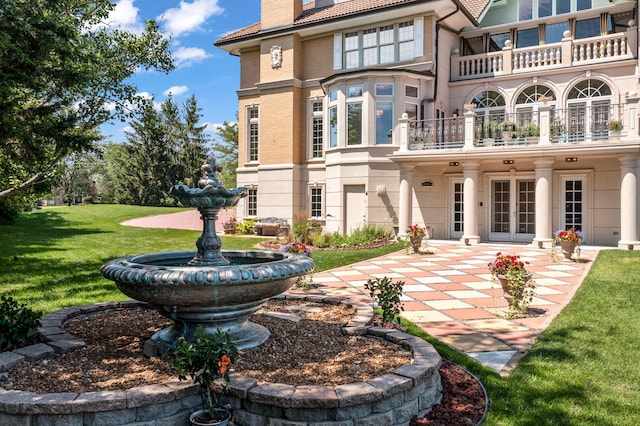 rear view of property featuring a yard, a balcony, and a patio