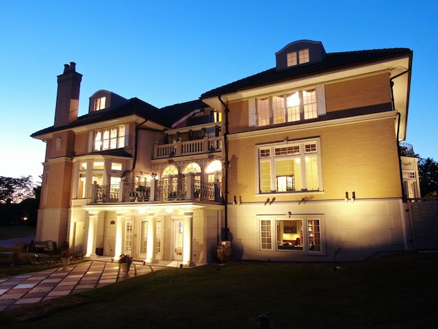 back house at dusk with a balcony