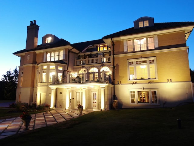 back house at dusk with a balcony