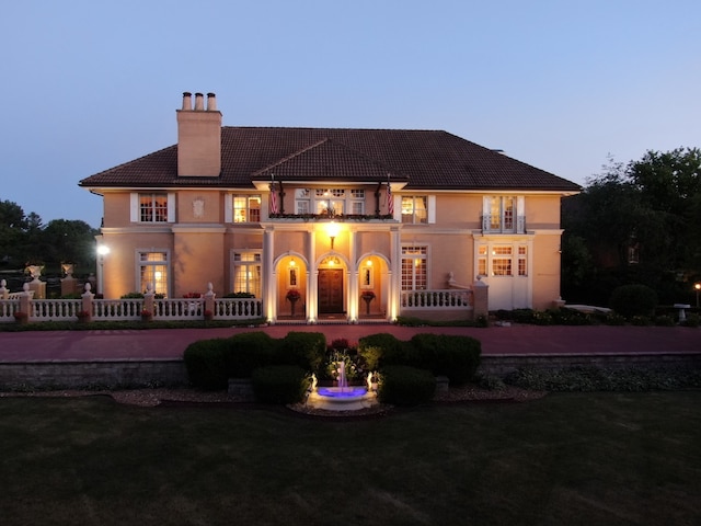 back house at dusk with a balcony