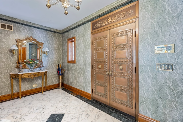 entryway with crown molding and a chandelier