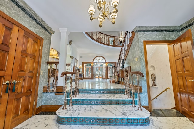 entryway with a chandelier, french doors, ornate columns, and crown molding