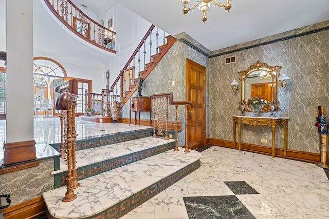 entryway featuring crown molding, a towering ceiling, and an inviting chandelier