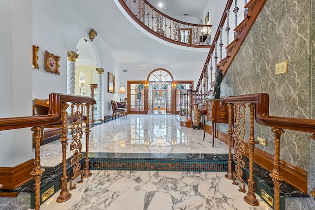 foyer featuring french doors, a towering ceiling, and crown molding