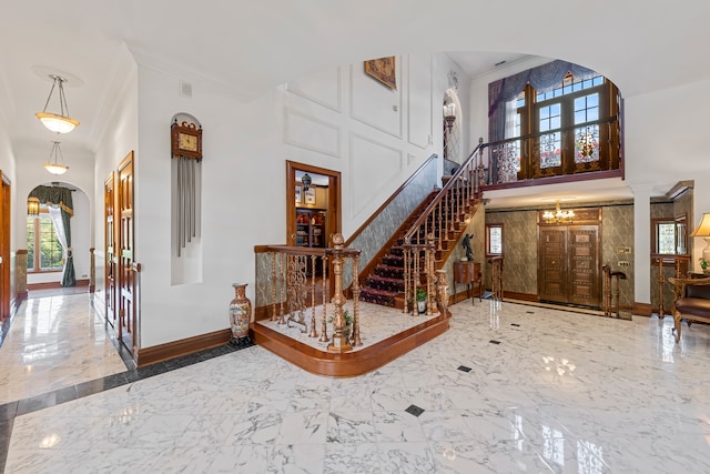 entrance foyer featuring a chandelier, a high ceiling, and crown molding