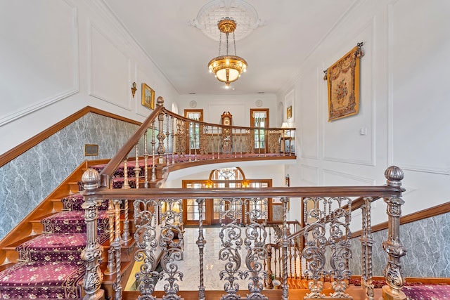 stairway with a notable chandelier and ornamental molding