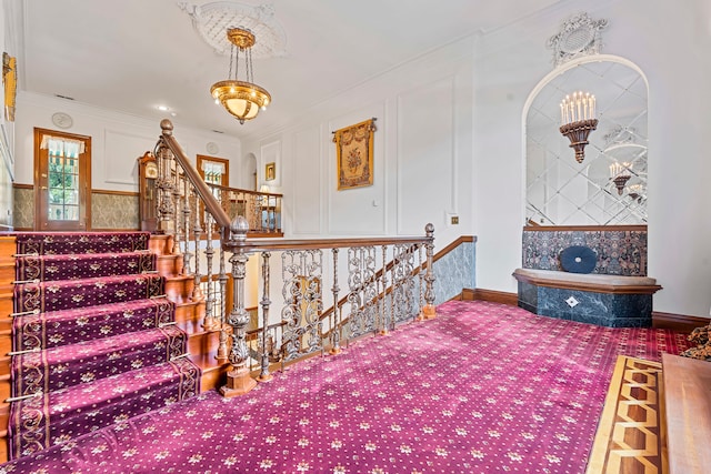 stairway with a notable chandelier and ornamental molding