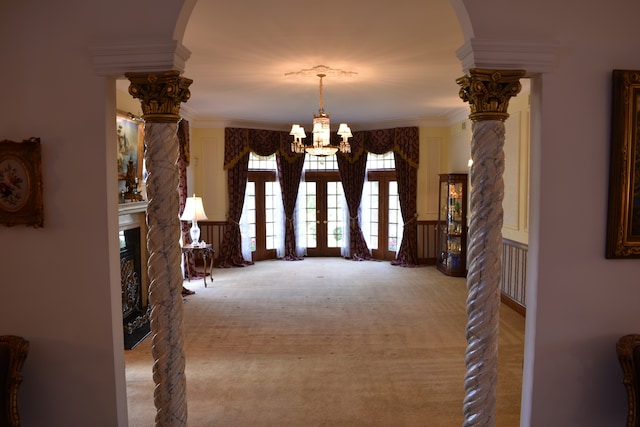 interior space with french doors, light colored carpet, an inviting chandelier, and crown molding