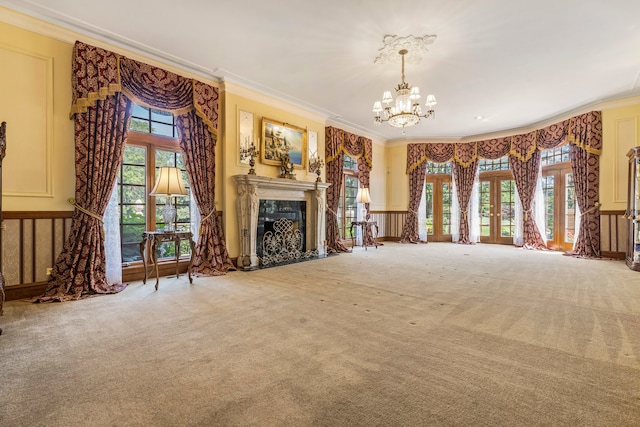 unfurnished living room with carpet floors, plenty of natural light, ornamental molding, and a notable chandelier