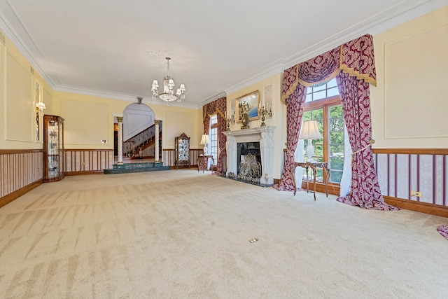 unfurnished living room with light colored carpet, ornamental molding, a high end fireplace, and an inviting chandelier