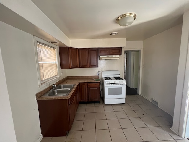 kitchen with white range with gas stovetop, sink, and light tile floors