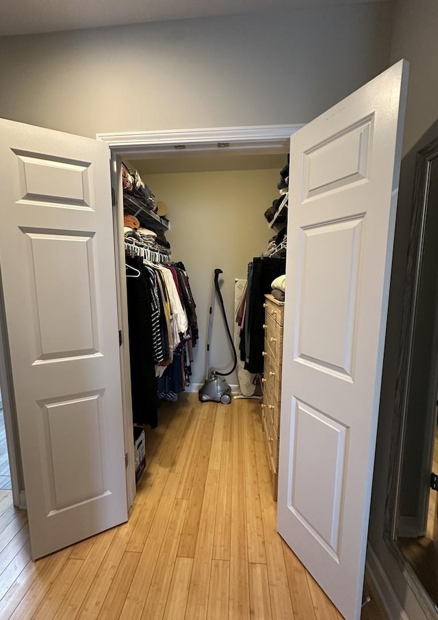 walk in closet with light hardwood / wood-style floors