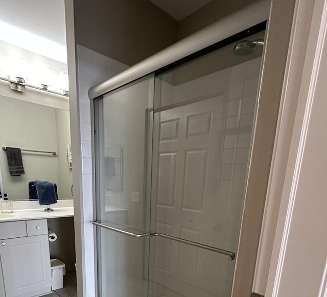 bathroom featuring hardwood / wood-style floors, a shower with door, and vanity