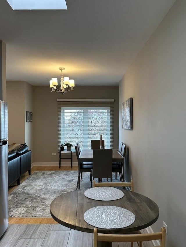 dining room featuring a skylight, a chandelier, and wood-type flooring