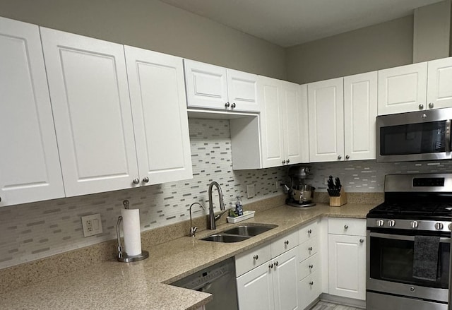 kitchen with appliances with stainless steel finishes, white cabinets, and tasteful backsplash