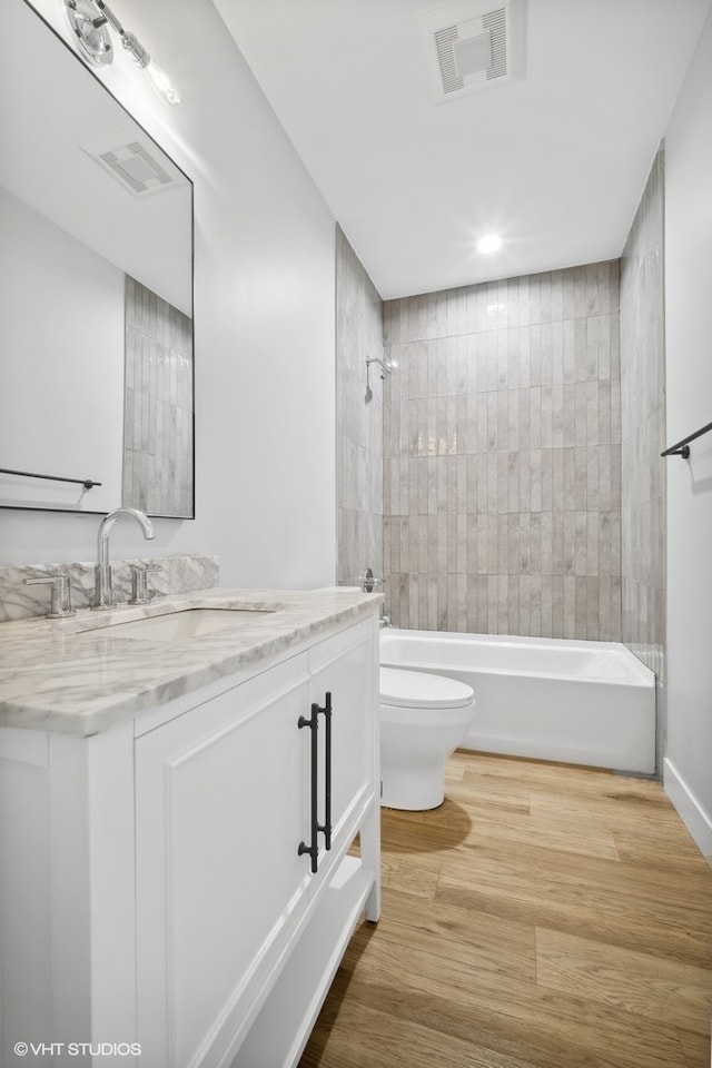 full bathroom with vanity, toilet, tiled shower / bath, and wood-type flooring