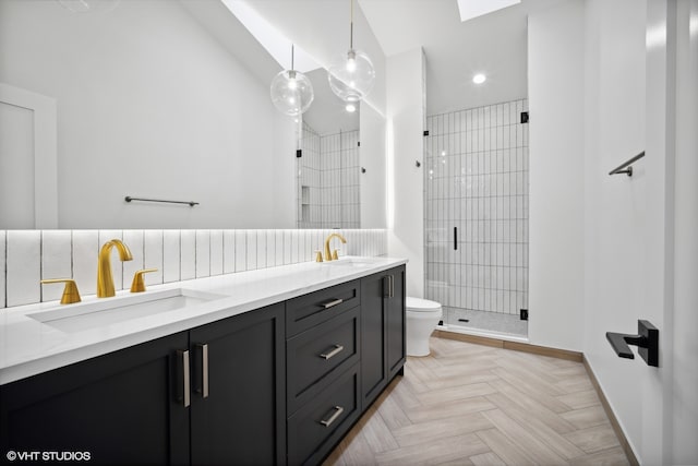 bathroom with double sink, a tile shower, parquet flooring, vanity with extensive cabinet space, and toilet