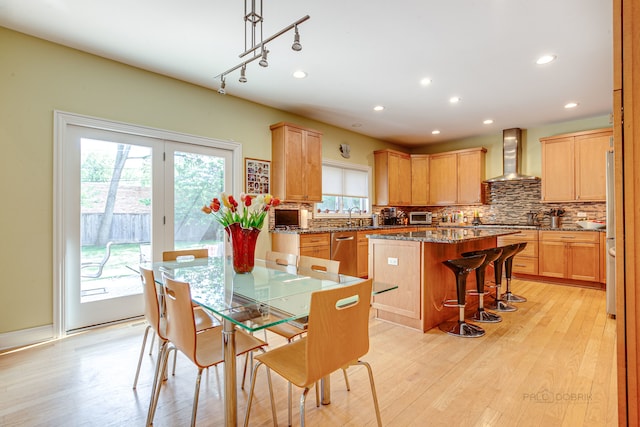 dining space featuring rail lighting, sink, and light hardwood / wood-style flooring