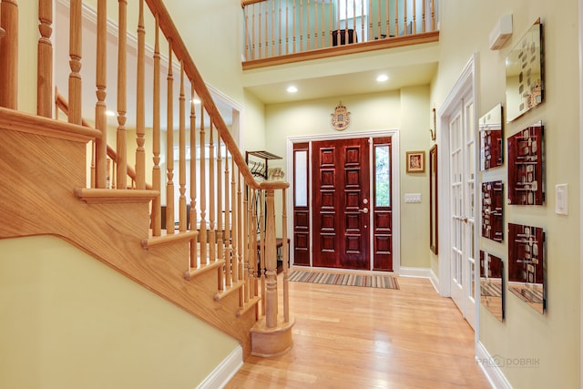 foyer entrance with light hardwood / wood-style flooring, a high ceiling, and french doors