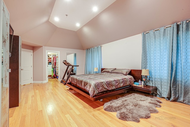 bedroom featuring lofted ceiling, a spacious closet, a closet, and light hardwood / wood-style flooring