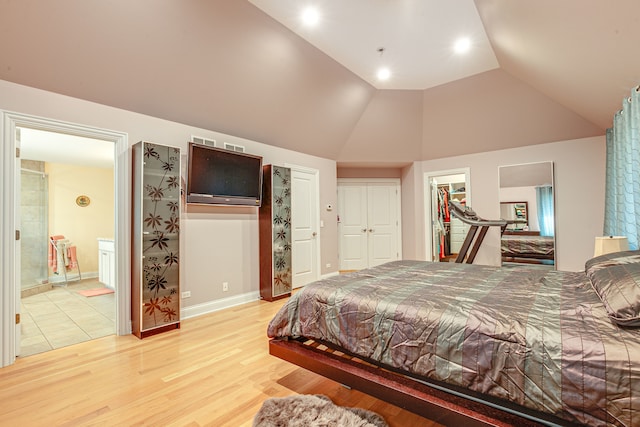 bedroom with lofted ceiling, ensuite bathroom, and light wood-type flooring