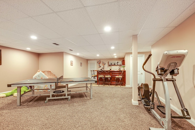 interior space featuring a paneled ceiling, light carpet, and indoor bar