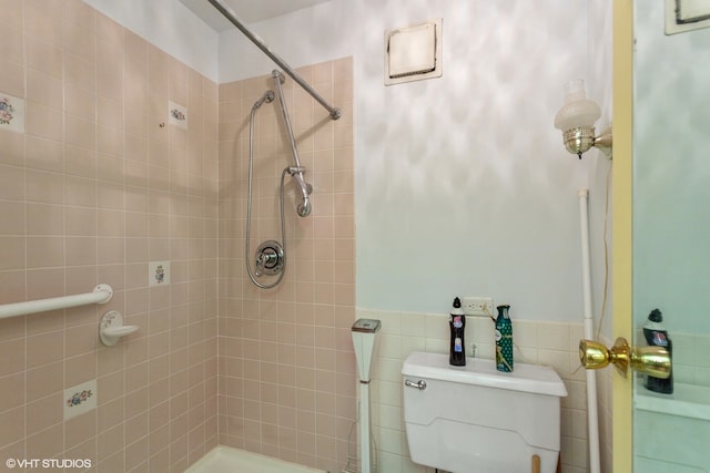 bathroom with toilet, tile walls, and tiled shower