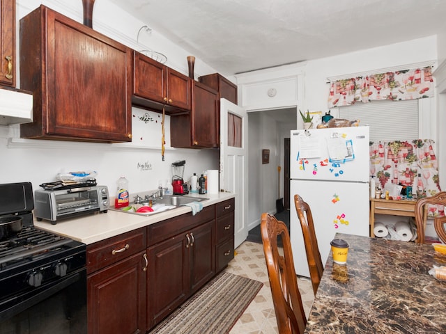 kitchen featuring light tile flooring, range with gas stovetop, fume extractor, and white refrigerator