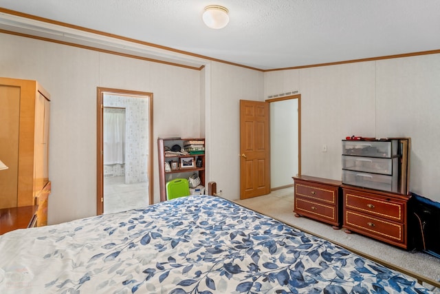 carpeted bedroom with ensuite bath, a textured ceiling, and ornamental molding