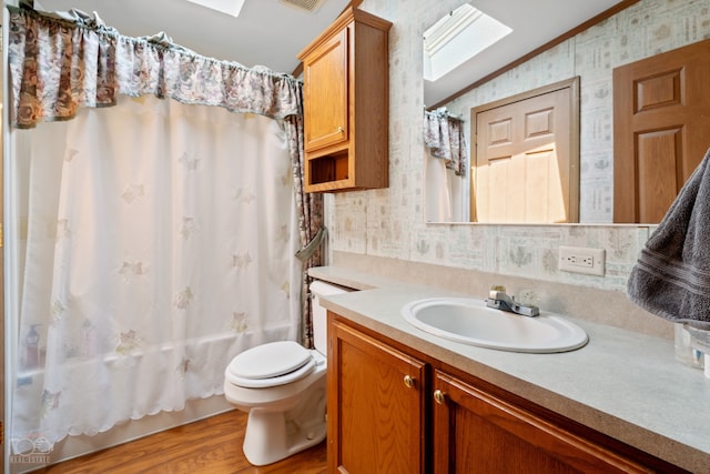 full bathroom featuring lofted ceiling with skylight, hardwood / wood-style flooring, crown molding, toilet, and vanity