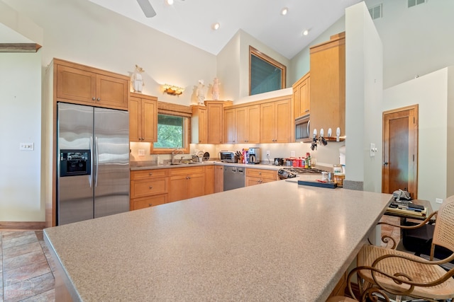 kitchen featuring appliances with stainless steel finishes, tile floors, a kitchen bar, sink, and high vaulted ceiling