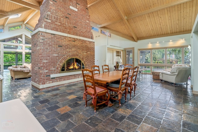 tiled dining space with beam ceiling, high vaulted ceiling, brick wall, and a fireplace