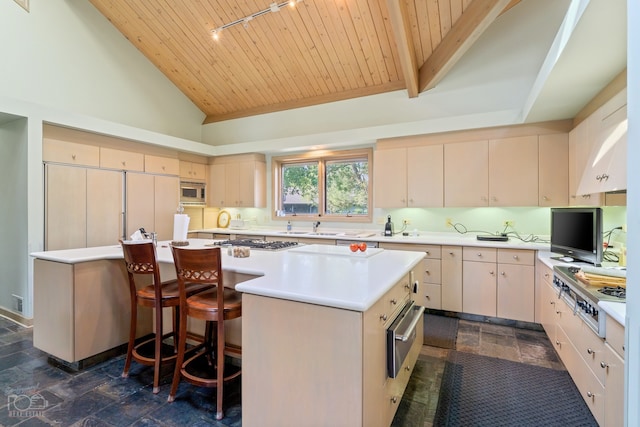 kitchen with appliances with stainless steel finishes, a kitchen island, dark tile flooring, a kitchen breakfast bar, and wooden ceiling