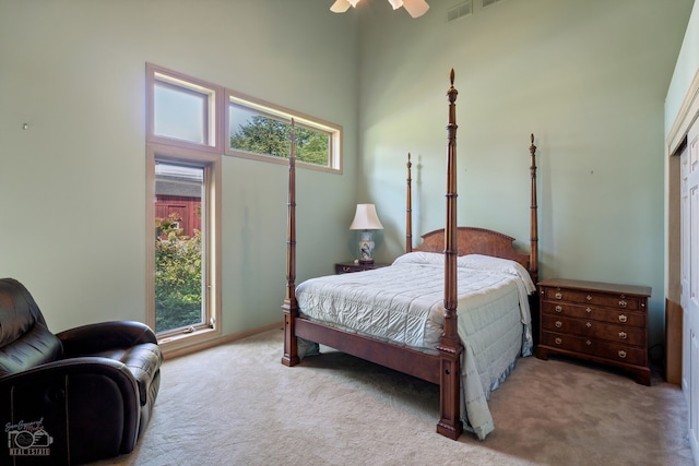 bedroom with multiple windows, light carpet, ceiling fan, and a towering ceiling