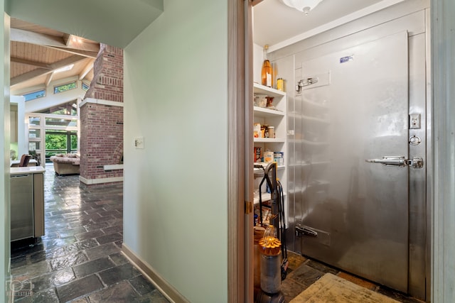 hallway featuring brick wall and dark tile floors