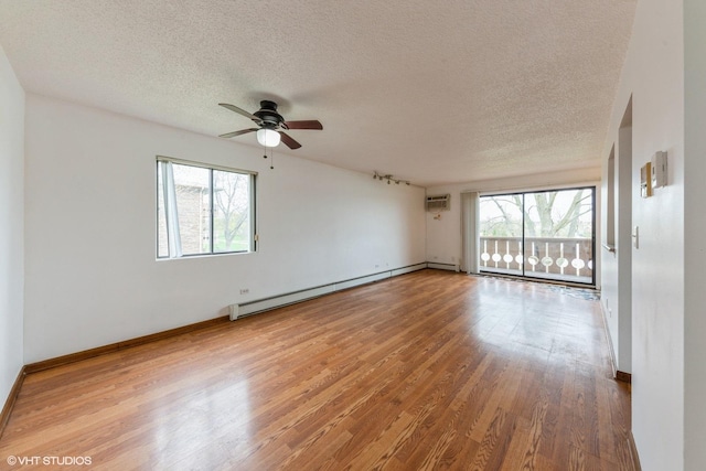 unfurnished room featuring wood finished floors, a ceiling fan, a wall mounted AC, and plenty of natural light