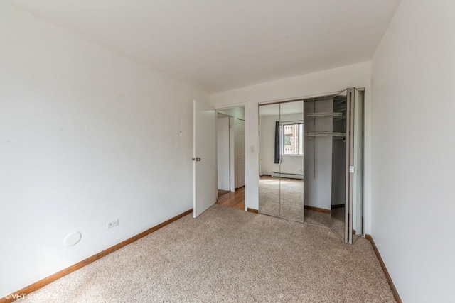 unfurnished bedroom featuring a baseboard heating unit, a closet, carpet, and baseboards