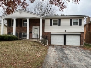 split foyer home with a garage, covered porch, and a front lawn