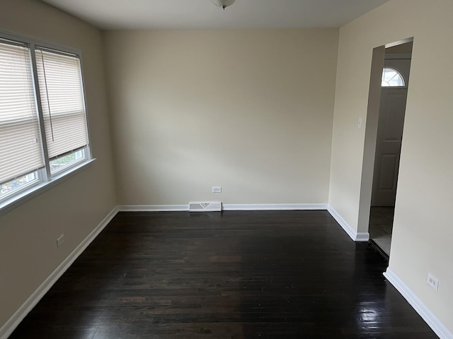 empty room with dark wood-type flooring and plenty of natural light