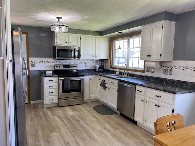 kitchen featuring white cabinets, hanging light fixtures, appliances with stainless steel finishes, and sink