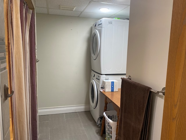 clothes washing area with tile floors and stacked washer / drying machine