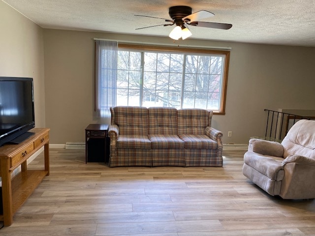 living room featuring a textured ceiling, ceiling fan, light wood-type flooring, and plenty of natural light