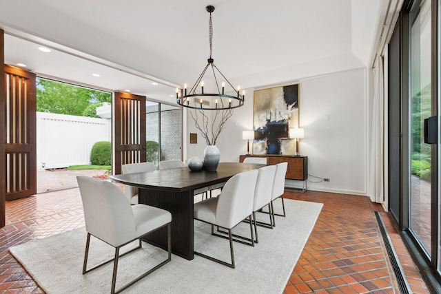 dining space with a wall of windows, brick floor, an inviting chandelier, and recessed lighting