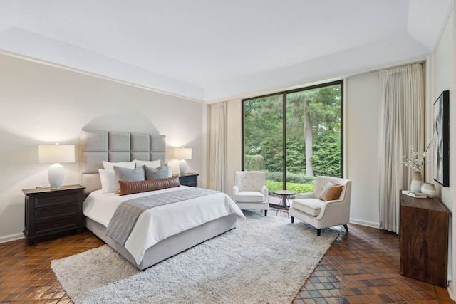 bedroom featuring brick floor, multiple windows, and baseboards